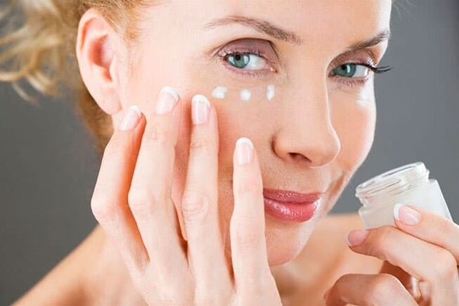 Woman applying face cream with anti-aging effect. 