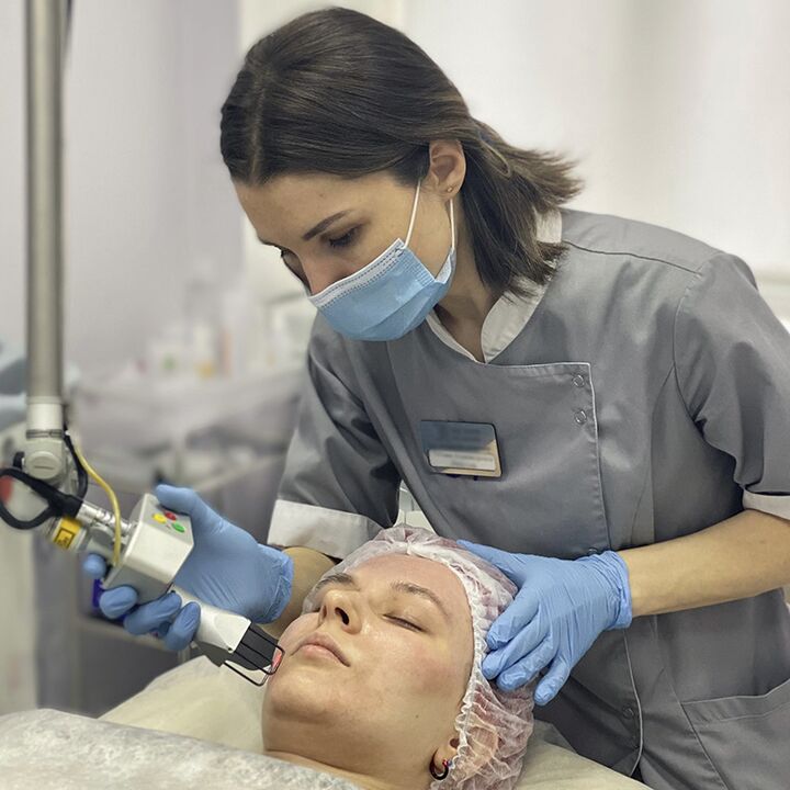 A cosmetologist performs a fractional laser facial rejuvenation procedure